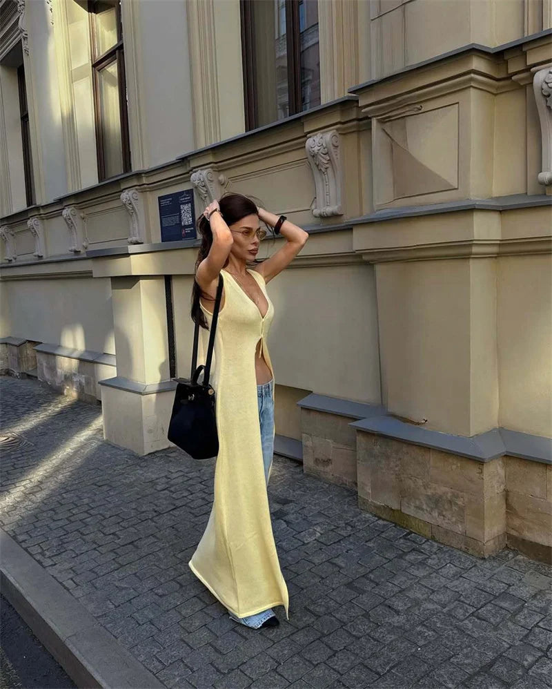 Woman in a yellow dress standing on a street with a building in the background