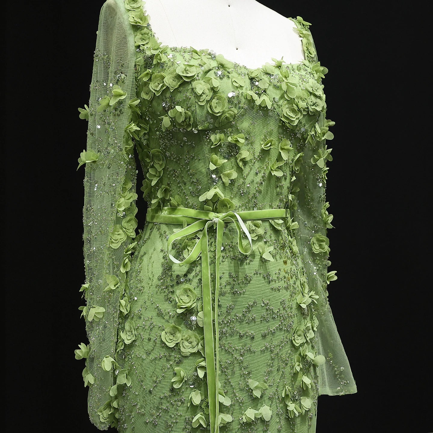 Green lace dress on a mannequin against a black background