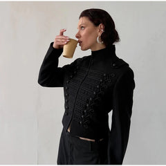 Woman in a black coat drinking from a yellow cup against a plain background