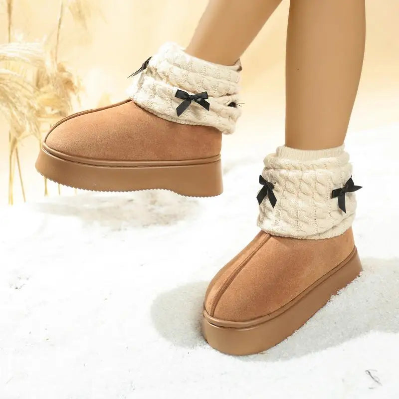 Tan winter boots with white cuffs featuring black bows on a soft white background