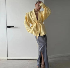 Person wearing a yellow jacket and gray pants against a plain background