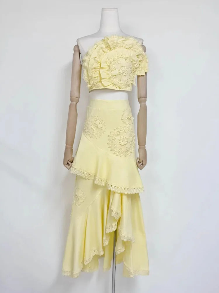 Yellow floral lace one-shoulder crop top with an asymmetric ruffle midi skirt on mannequin.