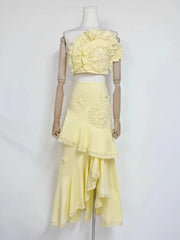 Yellow floral lace one-shoulder crop top with an asymmetric ruffle midi skirt on mannequin.