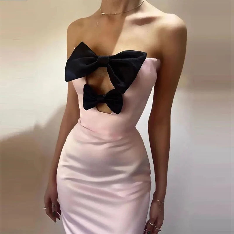 Pink dress with a large black bow on a plain background
