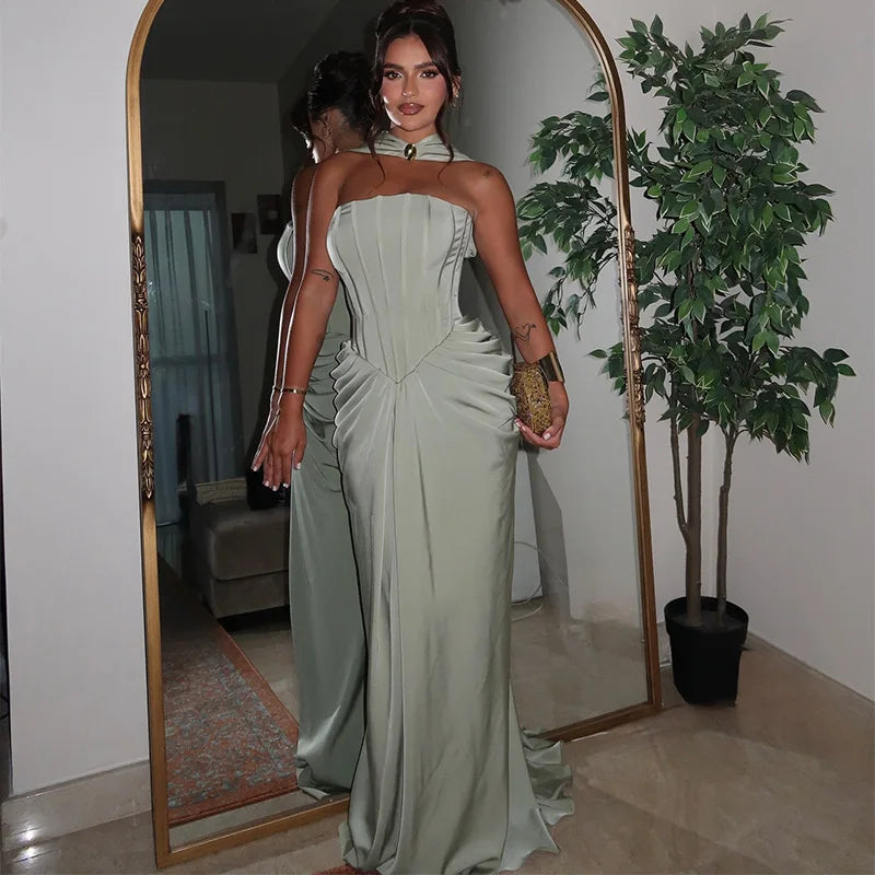 Woman in a strapless green gown standing in front of a mirror in a room with a plant.