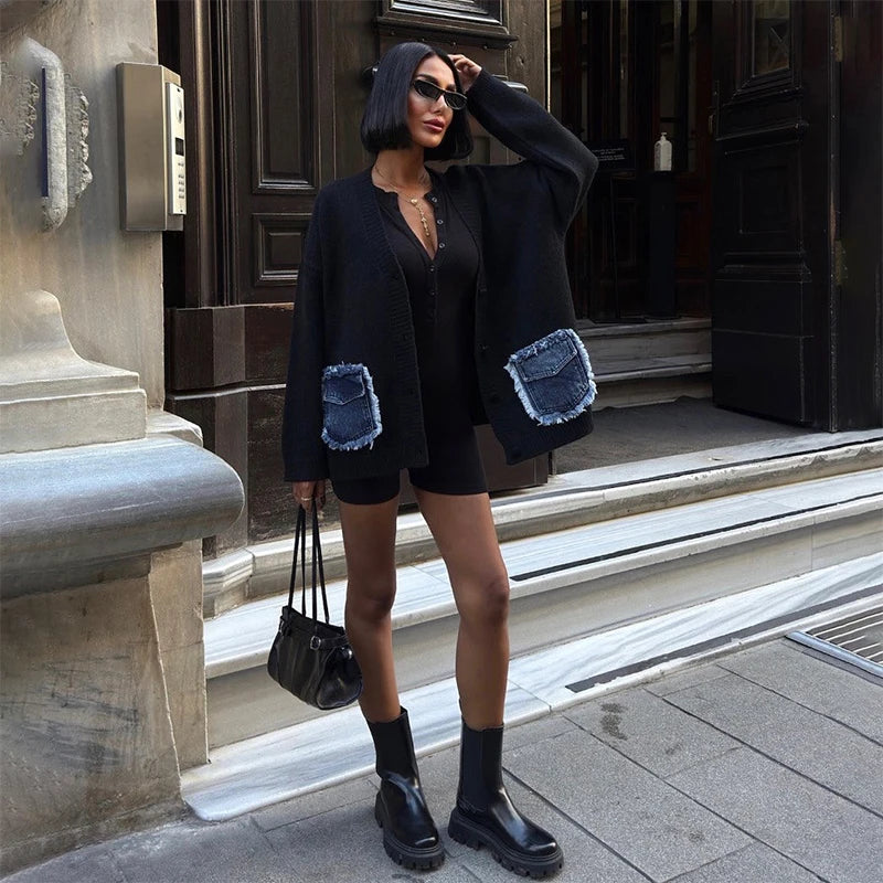Woman in a stylish outfit with a black jacket and denim patches, standing on steps.