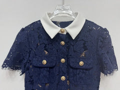 Navy lace dress with white collar and gold buttons on a hanger against a light gray background