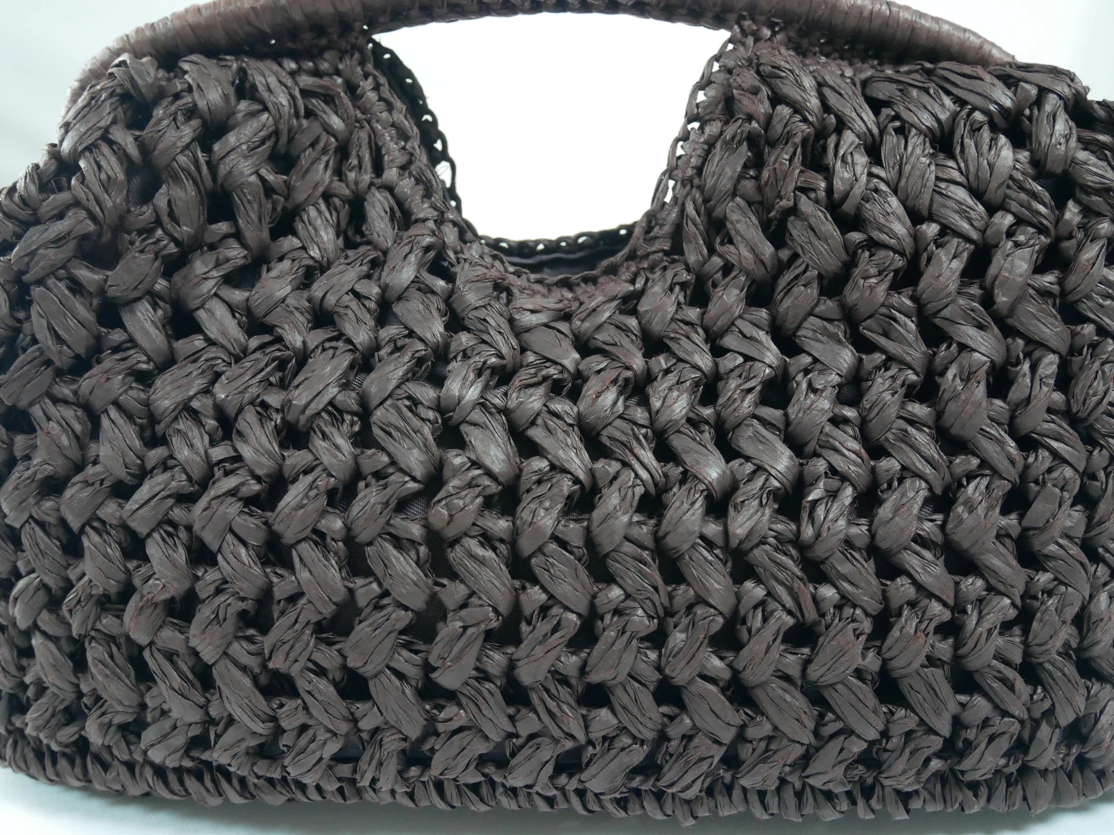 Close-up of a woven brown handbag on a white background