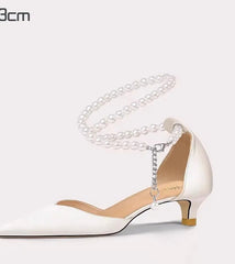 White high-heeled shoe with a chain detail on a white background