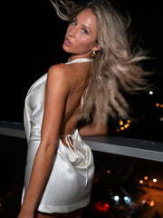 Woman in a white dress with a blurred night-time cityscape background