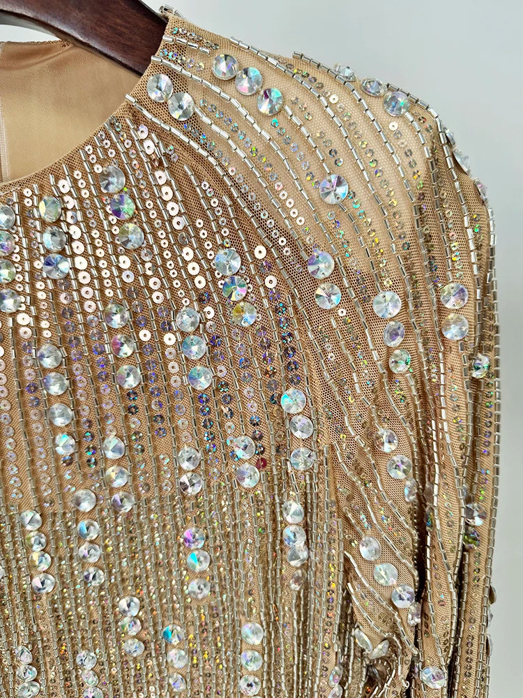 Close-up detail of the intricate beadwork and embellishments on a gold long sleeve mini dress.