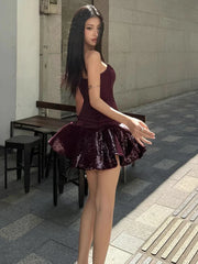 Woman in a burgundy dress standing on a sidewalk with a building in the background