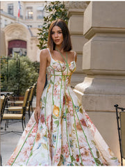 Strappy corset bustier maxi dress with floral motif and green trim, worn by a model standing outdoors.