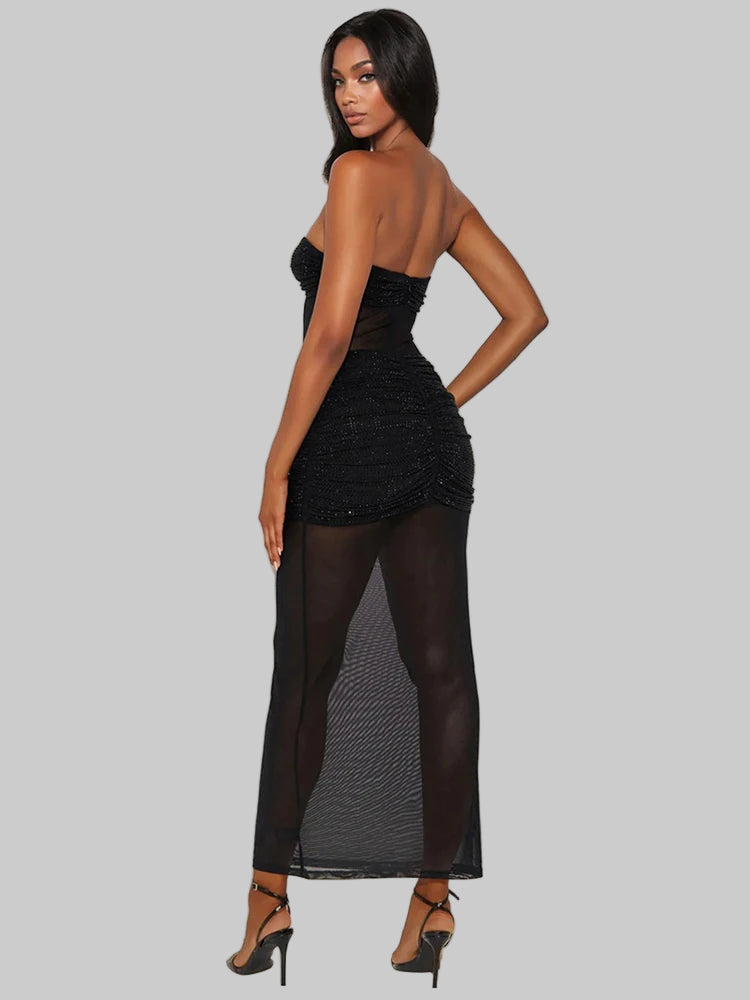 Woman wearing a black dress with sheer panels on a gray background