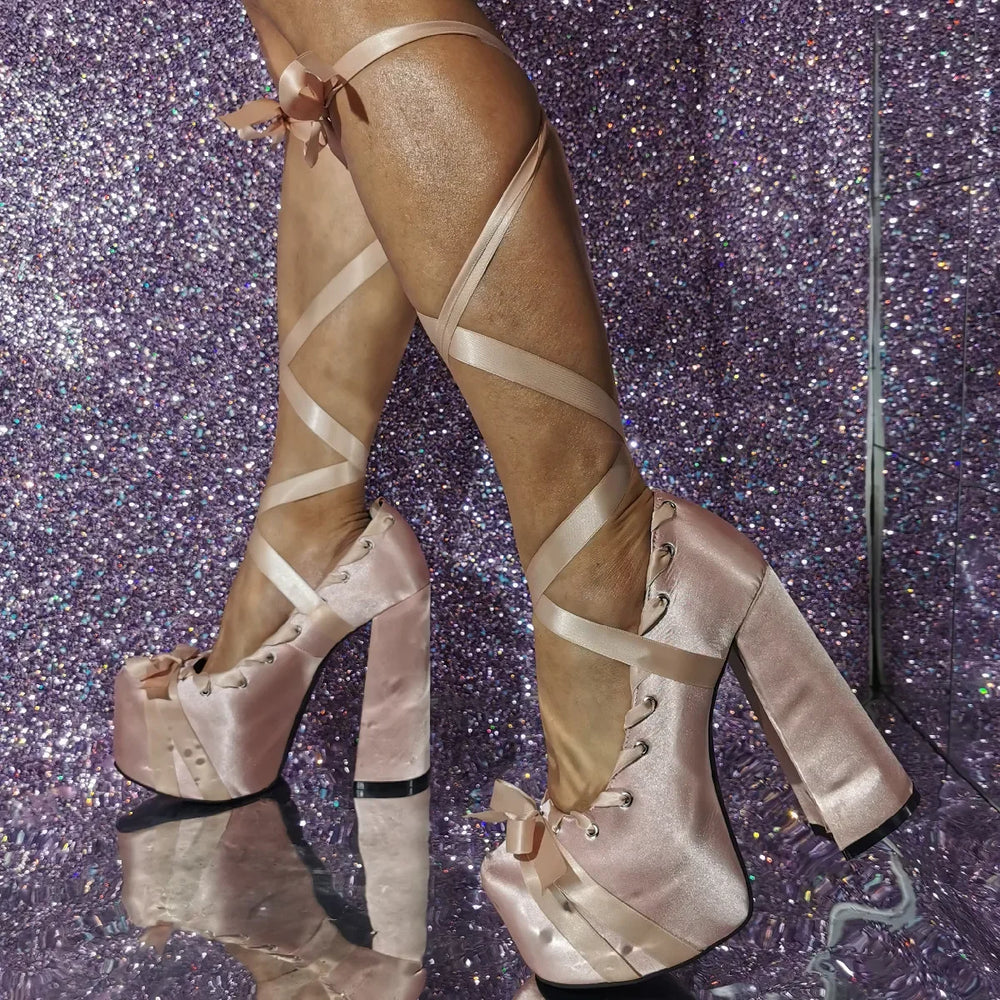 Beige satin platform boots with criss-cross straps on a glittery purple background