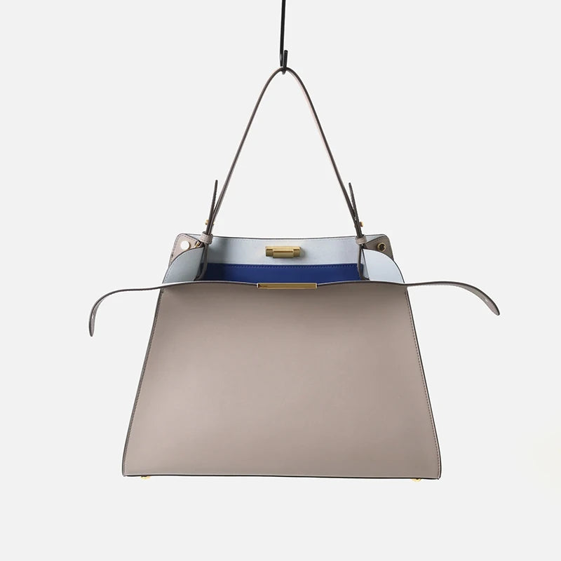 Leather trapezoid top handle bag with a blue interior.