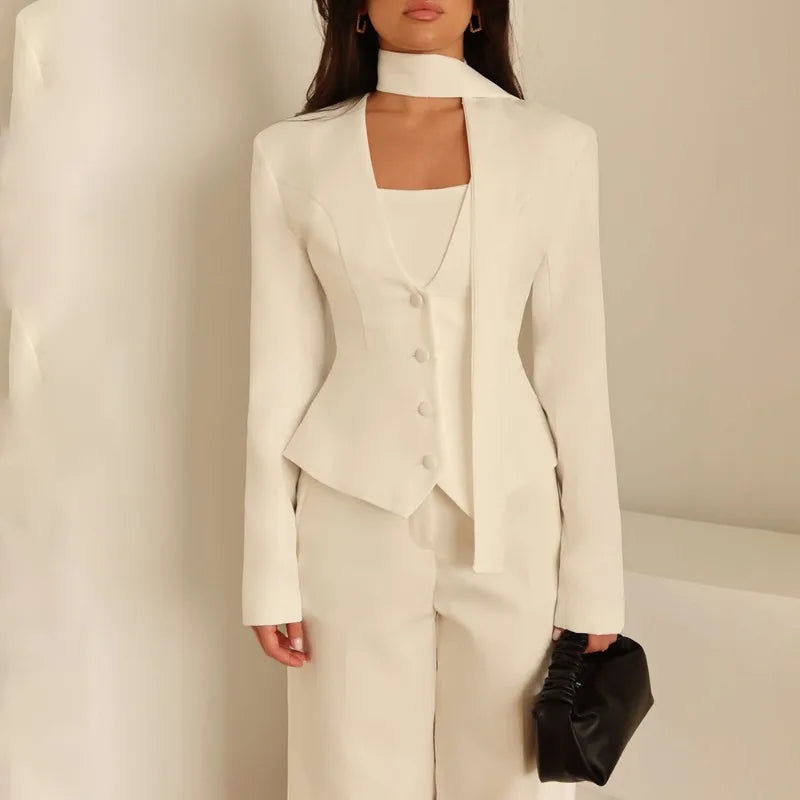 Woman wearing a white suit with a black clutch against a neutral background