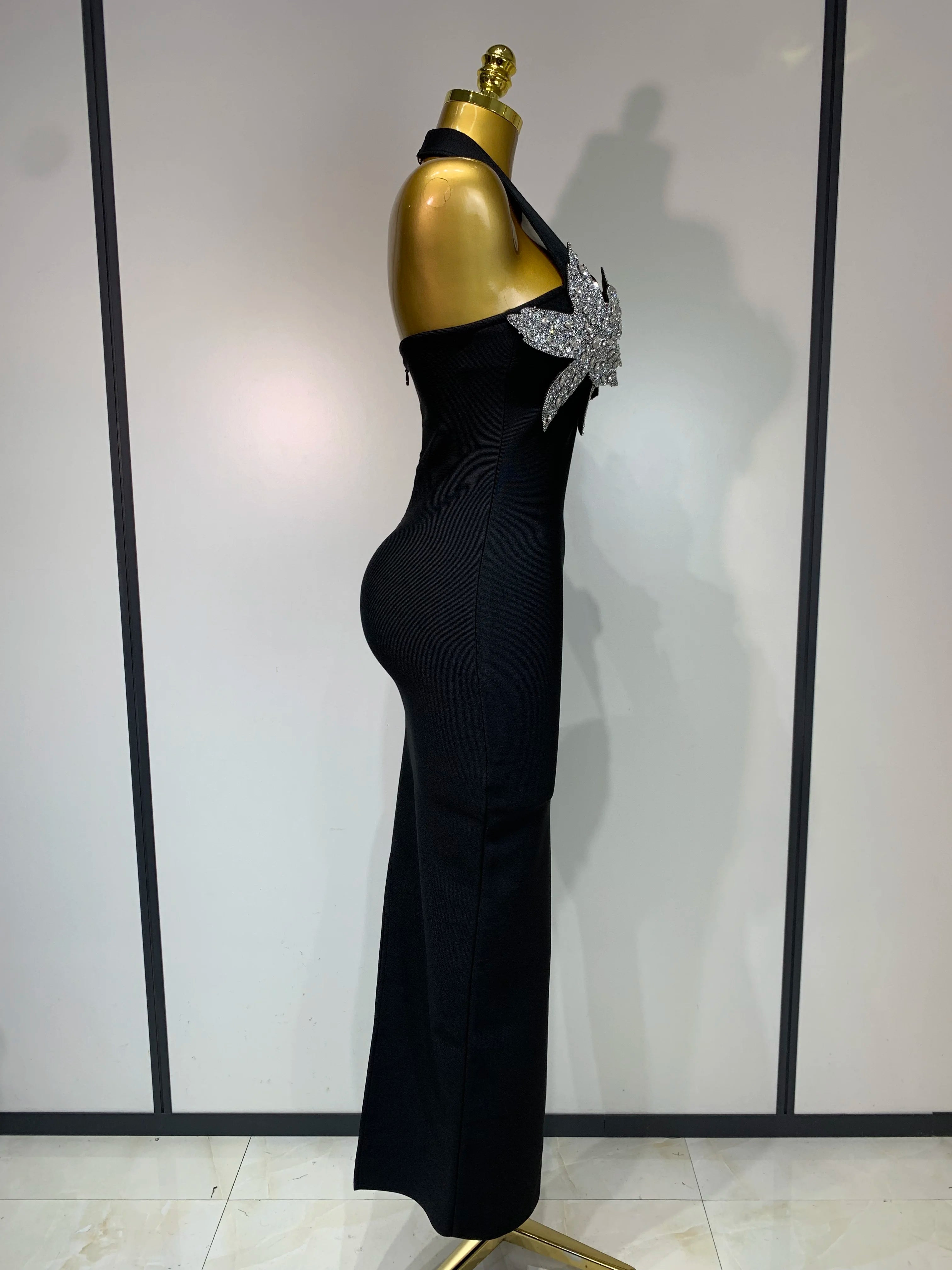 Black evening gown with a large bow on a mannequin against a white wall.