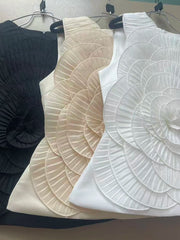 Three sleeveless tops in black, beige, and white on hangers against a neutral background.