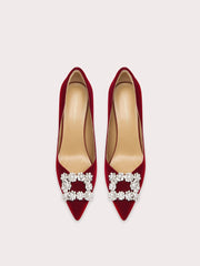 Red high-heeled shoes with pearl embellishments on a light gray background