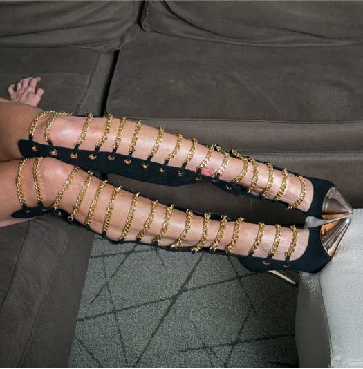 Person wearing gold studded high-heeled shoes on a couch.