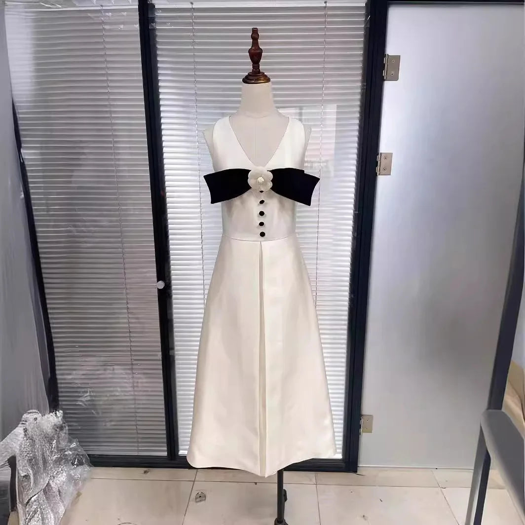 White dress with black bow on a mannequin against a glass door.