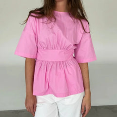 Person wearing a pink blouse with a plain background