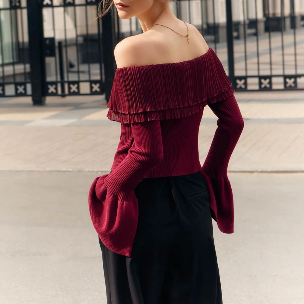 Woman wearing a burgundy off-shoulder top with ruffled details and a black skirt.