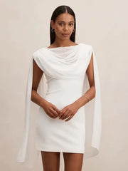 Woman wearing a white dress with a cape against a beige background
