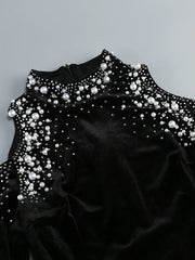 Black dress with pearl embellishments on a gray background