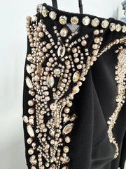 Detail of the beaded embellishments on the shoulder and sleeve of a black maxi dress.