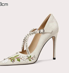 High-heeled shoe with floral design and embellishments on a white background
