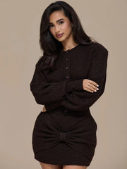 Woman wearing a black ribbed dress with a bow detail on a beige background