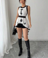 Woman wearing a black and white dress with floral patterns and black knee-high boots in a room.