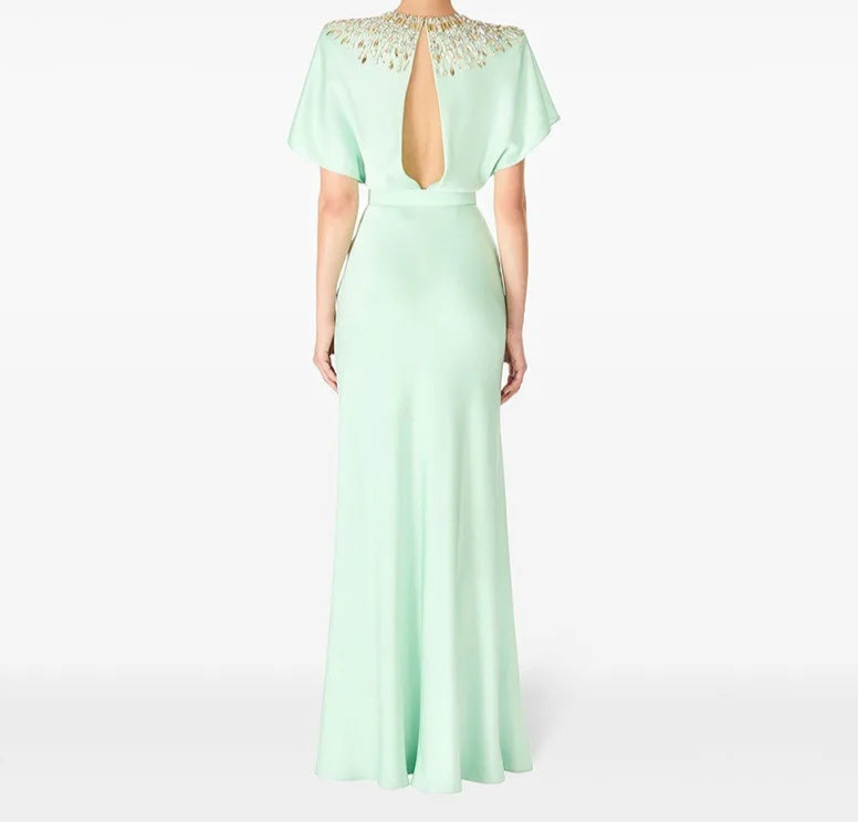 Mint green evening gown with open back on a white background