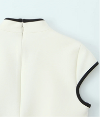 White blouse with black trim on a light blue background