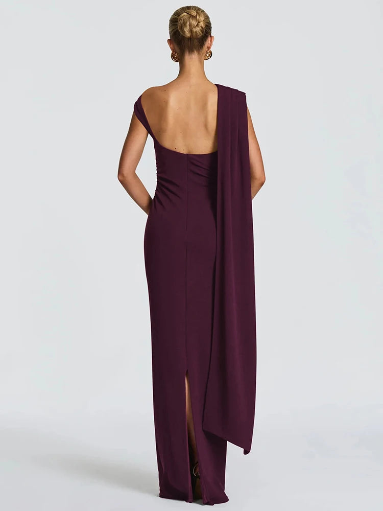 Woman wearing a long, one-shoulder purple dress with a slit on a white background