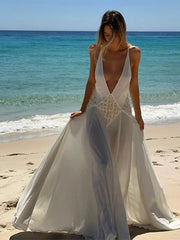 Woman in a white wedding dress with a deep neckline on a beach.