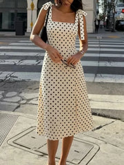 Woman wearing a square neck polka dot midi dress with tie shoulder straps