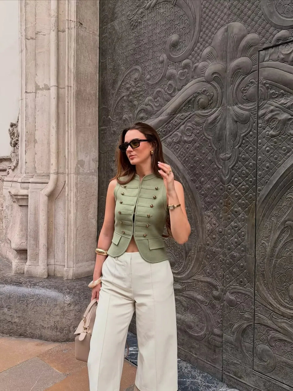 Woman wearing a knit military vest with cream trousers