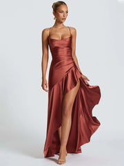 Woman wearing a rust-colored evening gown with a slit on a white background
