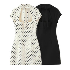Two dresses, one with a polka dot pattern and the other black, on a white background.
