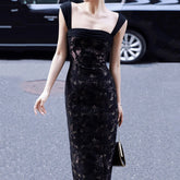 Woman wearing a black floral dress on a street.