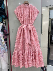 Pink lace dress with a bow tie on a hanger against a neutral background
