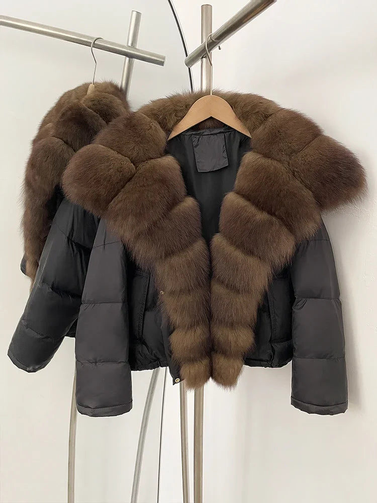 Black puffer jacket with brown fur collar hanging on a rack against a white wall.