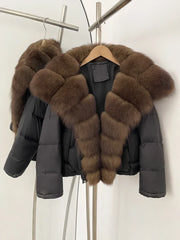 Black puffer jacket with brown fur collar hanging on a rack against a white wall.