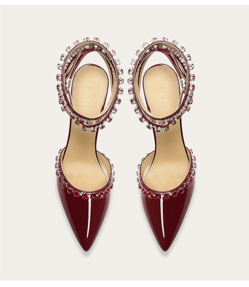 Pair of burgundy high-heeled shoes with embellishments on a light gray background