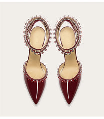 Pair of burgundy high-heeled shoes with embellishments on a light gray background