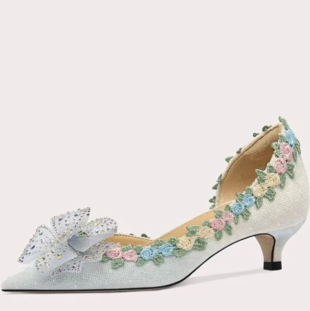 Decorative high-heeled shoe with floral and butterfly design on a light gray background