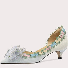 Decorative high-heeled shoe with floral and butterfly design on a light gray background
